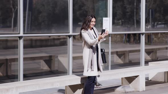 Businesswoman standing in front of glass facade using smartphone