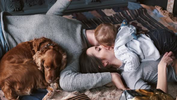 Parents Lying on Carpet with Dog and Holding Little Son