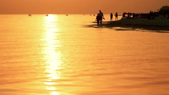 People Walking on the Beach at Sunset