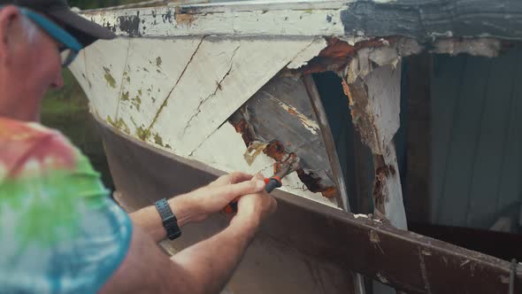 Carpenter chiseling rotten double diagonal mahogany planking on Seaplane Tender wood boat