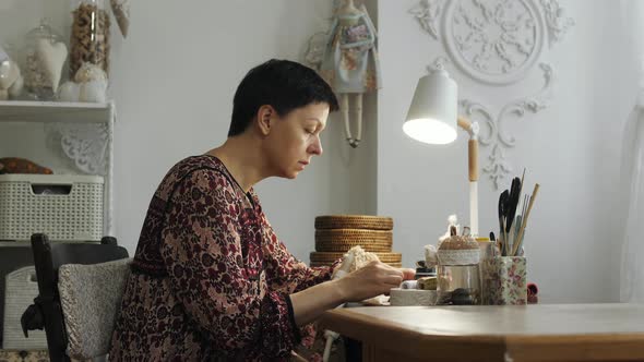 Woman drawing the eyes of a doll alt