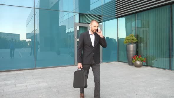 Young Businessman Talking on Phone and Walking in City Street