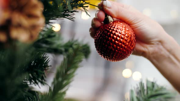 Girl decorates the Christmas tree. Close-up, hand, red Christmas ball