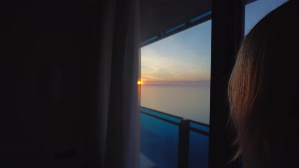 blonde in a white shirt admiring the sunset on the upper floor balcony