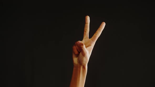 African American Man Showing Peace Gesture with Fingers Isolated on Black Background