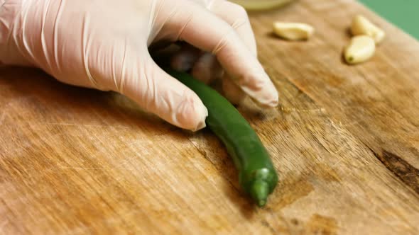 Female hands with a knife cut out hot pepper on a wooden board. 4k. Slow motion