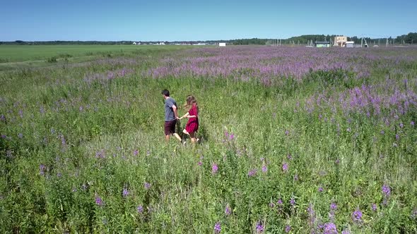 Pretty Couple Walks in Direction To Violet Blooming Plants