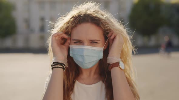 Young Caucasian Woman Portrait Takes Off Medical Mask at Sunny Day
