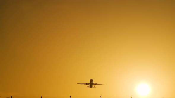 Take-off of a Passenger Plane From the Airport. Silhouette Against Background of Orange Sky Sunset. 