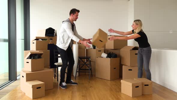 A Smiling Moving Couple Stacks a Few Cardboard Boxes and Hugs in a New Apartment - Piles of Boxes