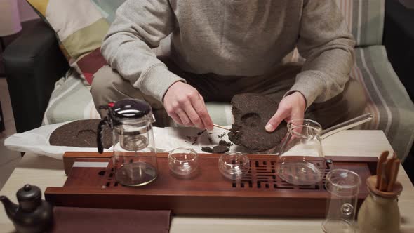 Traditional Eastern Chinese Tea Ceremony at Home. A Man Picks Pieces From a Tile of Compressed Black