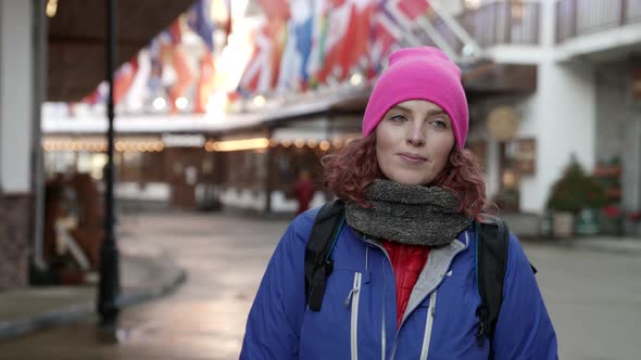 Adult Tourist Woman with Backpack Is Walking in Small City at Winter Day Portrait