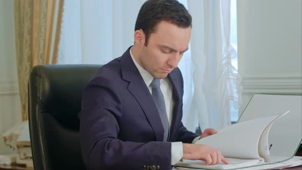 Businessman Reading Documents and Talking on Landline Phone