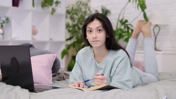 Teenage Girl Doing Homework on the Bed