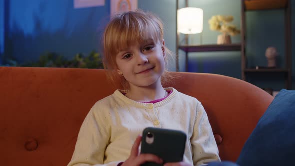 Child Toddler Hold Smartphone Watching Funny Cartoons Chatting with Friends on Couch Alone at Home