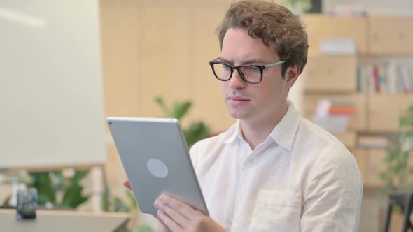 Portrait of Attractive Young Man Using Tablet in Modern Office