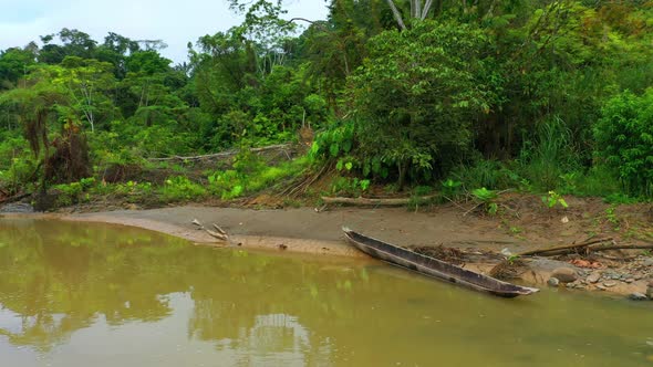 A traditional wooden canoe laying in a sand bank of a tropical river