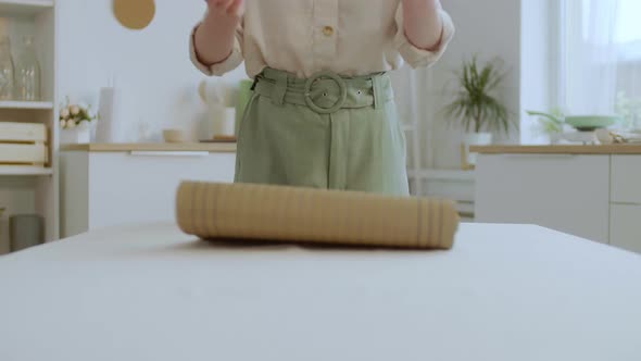Woman Unrolling Wooden Tablecloth on the Table