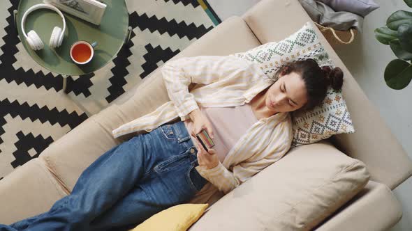 Woman Resting on Couch and Using Smartphone
