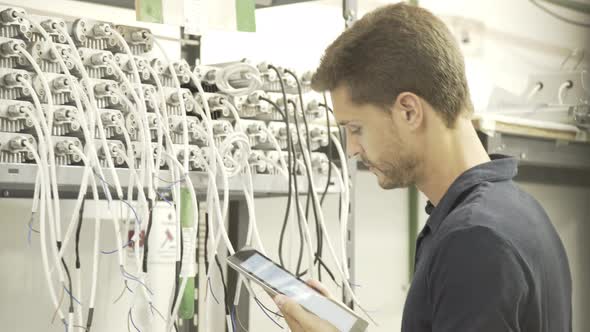 Electrician inspecting electrical equipment and using digital tablet