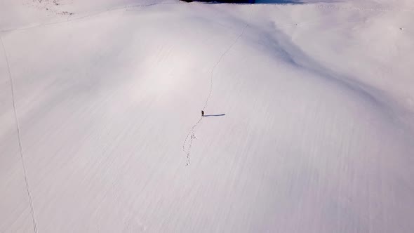 Young man walks through a snow field in Switzerland.