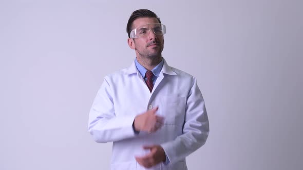 Young Happy Hispanic Man Doctor with Protective Glasses Thinking