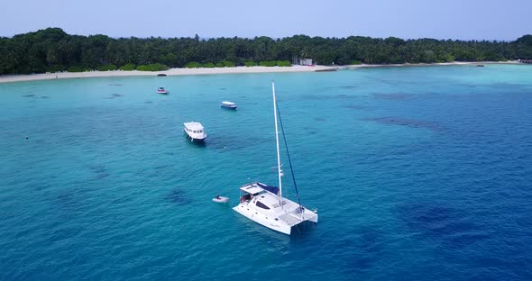 Wide aerial tourism shot of a white paradise beach and turquoise sea background in vibrant 4K