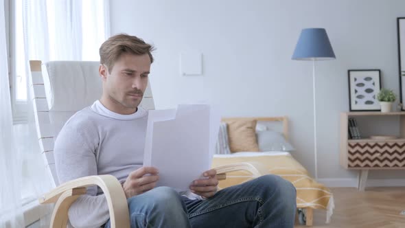 Adult Man Reading Documents While Sitting on Relaxing Chair
