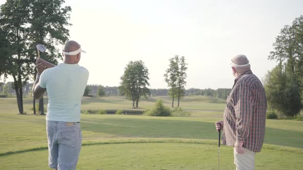 Confident Middle Eastern Golfer Swinging and Hitting Golf Ball on Beautiful Course