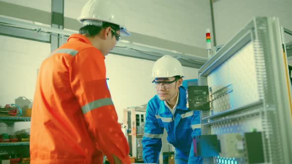 Male Asian engineer professional  having a discussion standing by the machine in the factory