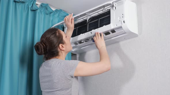 Young Woman Apartment Owner Tightens Air Conditioner Screw