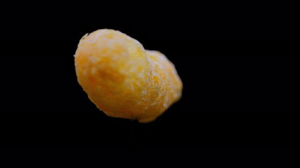 Cheesy Puff Snack Food Turning Slowly, Isolated On Black Background - close up