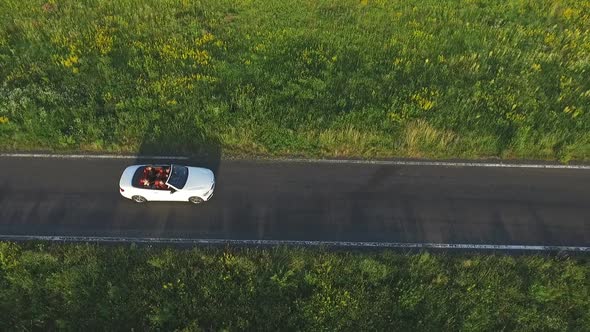 Aerial Shot of White Convertible Car Riding Through Empty Rural Road. Four Young Unrecognizable