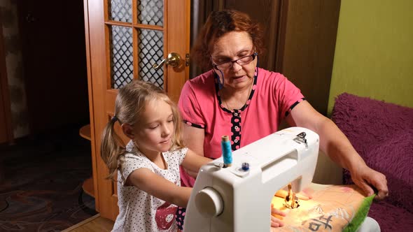 Girl with Grandma Using Sewing Machine Together