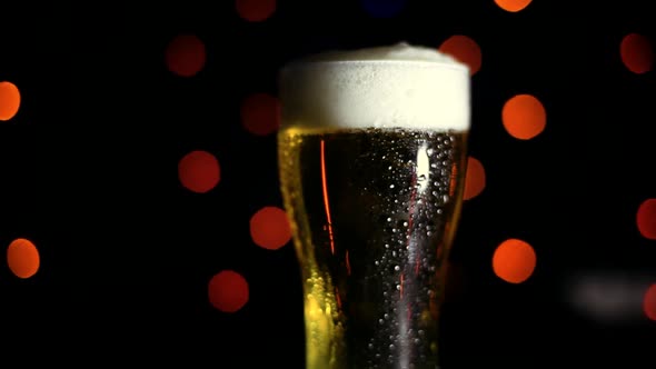 A Glass of Cold Beer on a Black Background with Colored Lights