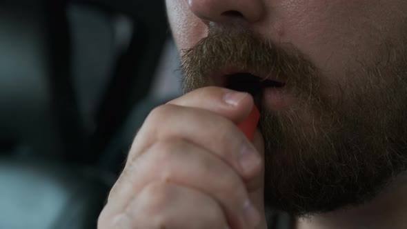 Close Up View of Unrecognizable Bearded Man Sitting in Car Smoking Electronic Cigarette and Blowing