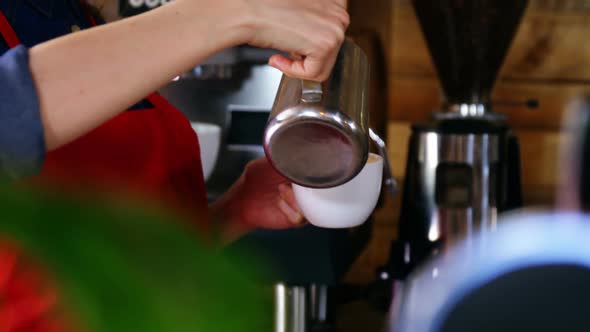 Waitress pouring milk in coffee at counter