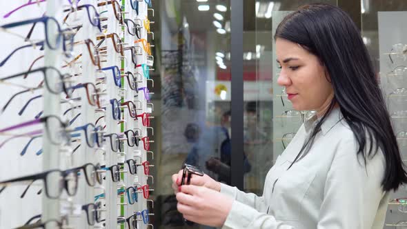 Young Woman Inspects Glasses in an Optics Store