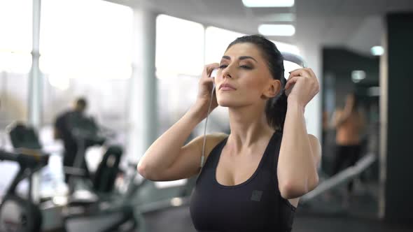Active Woman Putting on Headphones and Enjoying Music in Gym, Sport Inspiration