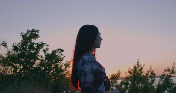 Young girl on the background of sunset looks into the distance