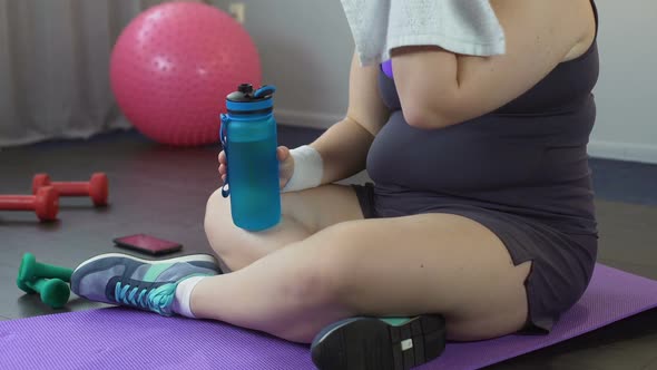 Plump Lady Restoring Water Balance and Breath After Exhausting Home Workout