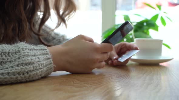 Girl Holding a Smartphone and Credit Card Layout While Sitting in a Cafe