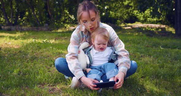 Young Mother with a Child on a Walk They Watching Interesting Educational Videos for Children