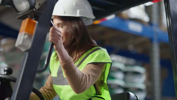 Live Camera Follows Confident Female Driver Autoloader Operator Sitting in Warehouse Forklift