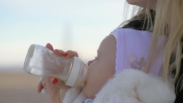 Mother feeding her baby girl outside