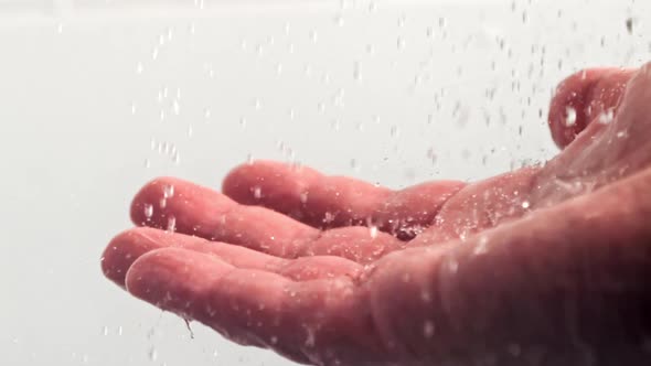 Drops of Water Pour on a Man's Hand