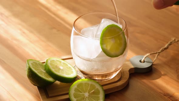 Man pouring soda into glass with ice and slice of lime. refreshing ice cold soda.