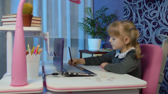 Child Schoolgirl Learning Lessons Distance Education at Home Sitting at Table Using Laptop Computer