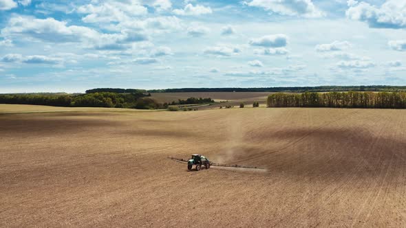 Modern technology of agriculture. Aerial view of the tractor spraying the chemicals on large field