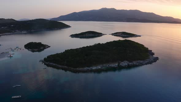 Silhouette of beautiful islets of Ksamil islands during golden hour with Corfu distant. Birds eye vi